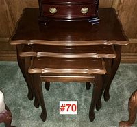Front-facing photo showing three nested wooden tables with curved edges and cabriole legs.