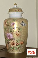 Full view of hand-painted porcelain ginger jar with decorated floral and bird motifs on a gold-tone background.