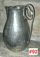 Front side view showing hammered texture and ornamental handle with leaf motif on pewter pitcher.