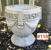 Side view of the cement planter showing Greek key band and relief grapevine details.