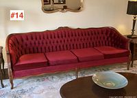 Full frontal view of the vintage French Provincial sofa showing four seat cushions and tufted back in deep red fabric with carved wooden frame.