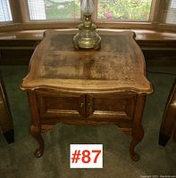 Top angled view of the vintage wooden side table showing curved edges and natural wood grain on surface with a lamp on top