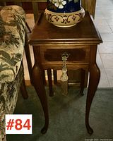 Side view showing wooden vintage side table with cabriole legs, tassel on drawer pull.