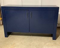 Front view of the indigo waterfall cabinet with two doors and slim gunmetal handles sitting on floor.