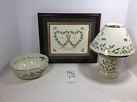 Three-piece set showing framed signed artwork, Lenox bowl, and holiday candle lamp.