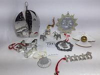 Full lot with all 10 metal Christmas ornaments arranged on white surface, showcasing various shapes and styles including Georg Jensen ball, reindeer, sun, angel and word ornament