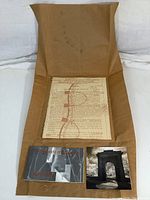 Overall view of signed Ken Hruby art print laid on unfolded brown paper packaging along with informational cards.