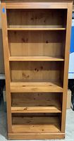 Front view of knotty pine bookcase showing five shelves and natural wood knots.