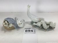 Two glazed porcelain duck and goose family figurines photographed against a white background with a label showing lot number 694.