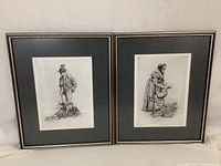 Pair of framed Paul Geissler etchings shown side by side against a plain background, both in black and white with dark mats and silver frames.