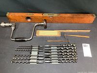 Full lot showing Stanley wooden level, Millers Falls hand brace drill, 13 twist drill bits, two small tack hammers, and wooden folding ruler.
