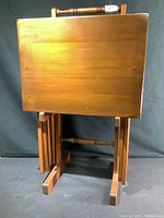 Front view of the stacked TV dinner tables on the caddy showing rectangular tabletops with maple finish and turned spindle handle