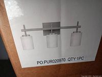 Label showing front view of the light fixture design with three frosted glass shades in brushed nickel finish.