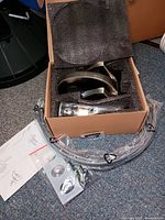 Box showing the faucet and installation parts, coiled hoses, instructions visible on the floor.