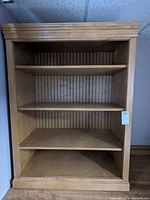 Front view of wooden bookcase showing four shelves and grooved back panel