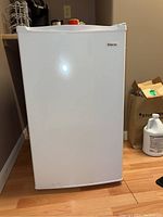 Front view of white Magic Chef dorm fridge with closed door.