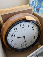Two round brown wooden framed clocks with white faces and black numerals inside a box with three wooden picture frames.