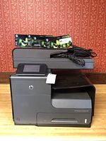 HP Officejet Pro X476dw printer with 4 packs of HP 971 ink cartridges on top, showing front and side views.