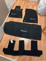 Photo showing all four black carpet Lexus RX floor mats arranged on a hardwood floor.