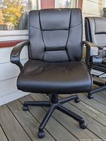 Front view of black rolling office chair showing padded seat, backrest, and armrests on five caster wheels.