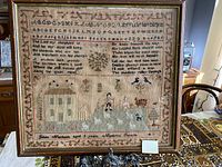 Frontal view of framed sampler showing full embroidery including alphabets, verse, pastoral scene and border.