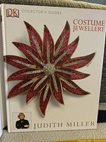 Front cover of the book showing red and gold floral brooch and author photo