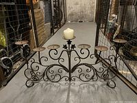 Front view of metal medieval-style candelabra with seven round candle holders and rustic finish.