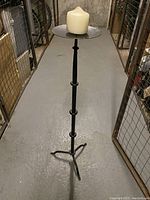 Front view of the metal floor candle holder with a candle placed on the tray.