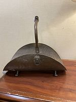 Front view showing lion head decoration and overall shape of the metal firewood holder.