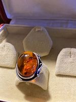 Front view of large oval amber set in silver Art Nouveau ring, shown on display stand.