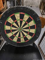 Front view of vintage dual-sided dart board showing cracked playing surface with black, red, and green segments.