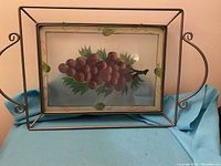 Full view of metal framed serving tray with hand painted grape design on glass insert.