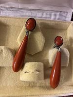 Front view of the pair of vintage silver earrings showing red acrylic stones in oval and teardrop shapes mounted on silver-tone metal with clip-on backs.