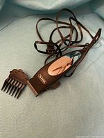Photo of WAHL hair clipper with attached comb and power cord on a blue background.
