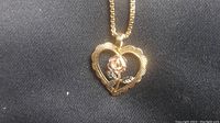 Heart-shaped pendant with rose motif on chain against black background