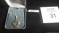 Yellow gold chain and heart pendant displayed in green velvet box, tag attached