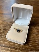 Ring displayed in a beige velvet presentation box on wooden surface