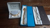 Jewelry lot includes three gold-tone pieces: Speidel bracelet with box, two gold-colored necklaces, and a small pin.