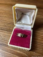 Gold ring displayed inside a vintage jewelry box with a pink velour interior and cream-colored exterior, marked 'Abramsky's' inside the lid.