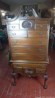 Full front view of highboy dresser showing upper and lower sections with decorative shell motif and brass handles.