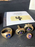 Group shot of ring, cufflinks and lapel pin on black background with MicroBid card