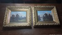 Two framed oil paintings side by side on wood surface