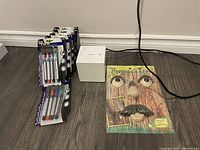 Photo of six dry erase marker packs, Personali Tree decorations (eyes, nose, mustache), and white Sony alarm clock on a wood floor.