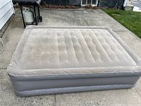 Full view of the inflated double wide, double high electric air mattress on concrete.