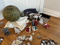 Christmas decorations including moss ball, lantern, figurines, garlands, and ornaments arranged on wooden floor.