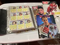 Photo showing hockey cards in sleeve pages inside a binder along with Beckett hockey magazines featuring prominent players on covers.