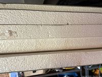 Close-up photo of stacked white foam insulation sheets showing surface texture and minor wear marks.