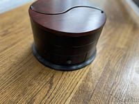 Closed view of compact round wooden jewelry box showing dark polished wood finish and curved lids.