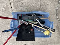 Overhead photo showing various car cleaning tools including squeegees, window brushes, a water spout, and a TV wall mount inside a blue plastic tote.