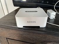 Front view of Sonos Connect device with visible branding and included power adapter cable.